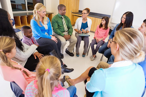 Parents, teachers, and children sitting together in a circle, engaging in open discussion as part of the Parent-on-Campus model.